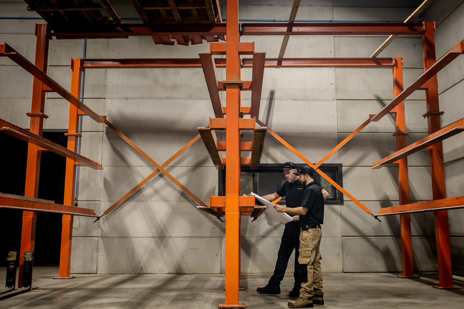 Photo de deux employées analysant un plan avec une structure d'acier orange