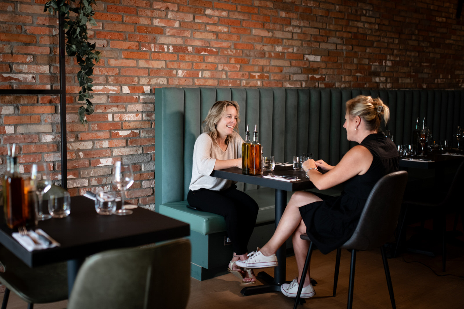 Photo horizontale de deux femmes discutant dans un restaurant sur une banquette