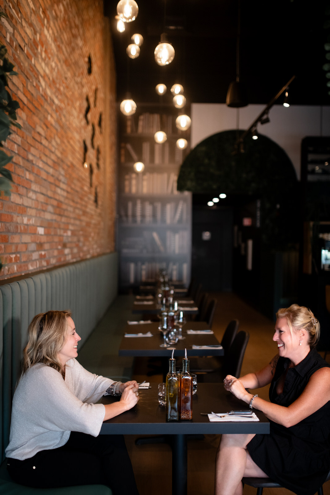 Photo verticale de deux clientes discutant dans un restaurant sur une banquette