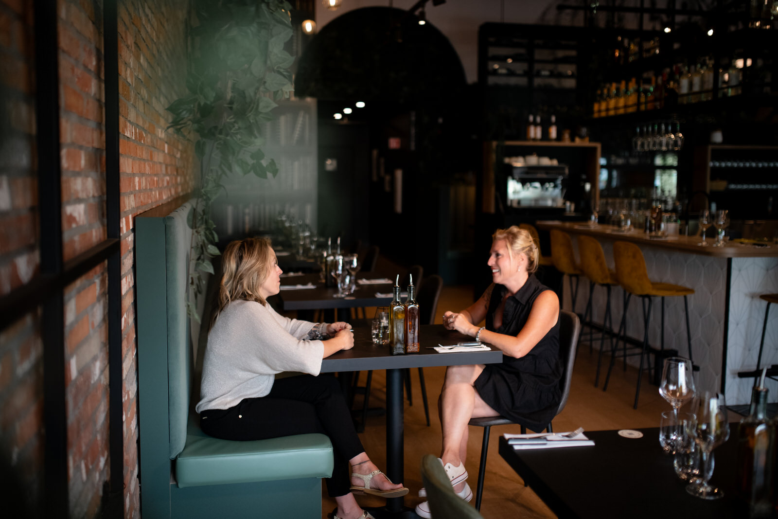 Photo horizontale de deux clientes discutant dans un restaurant sur une banquette