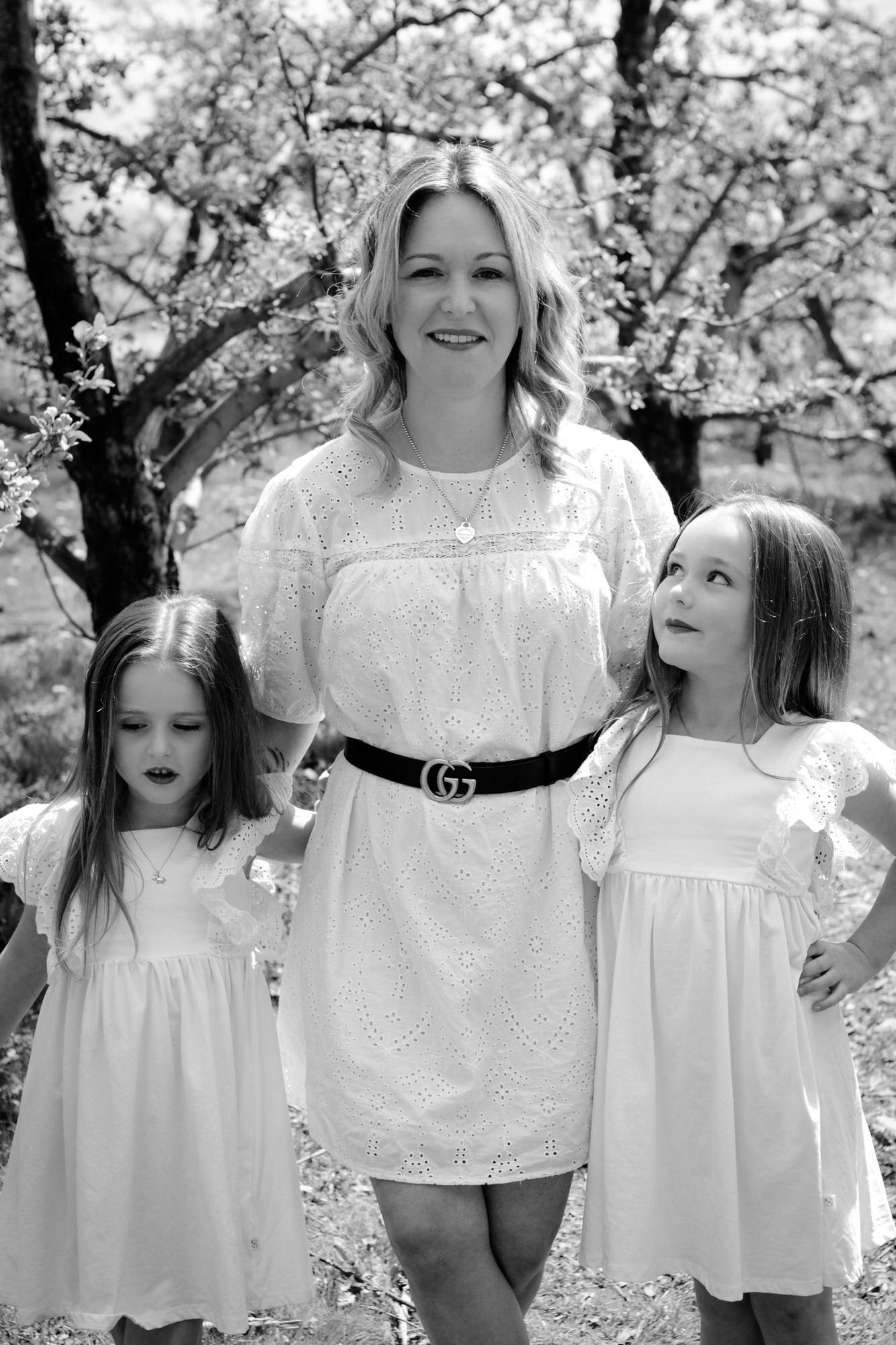 Photo portrait en noir et blanc d'une maman et ses jeunes filles en robe blanche