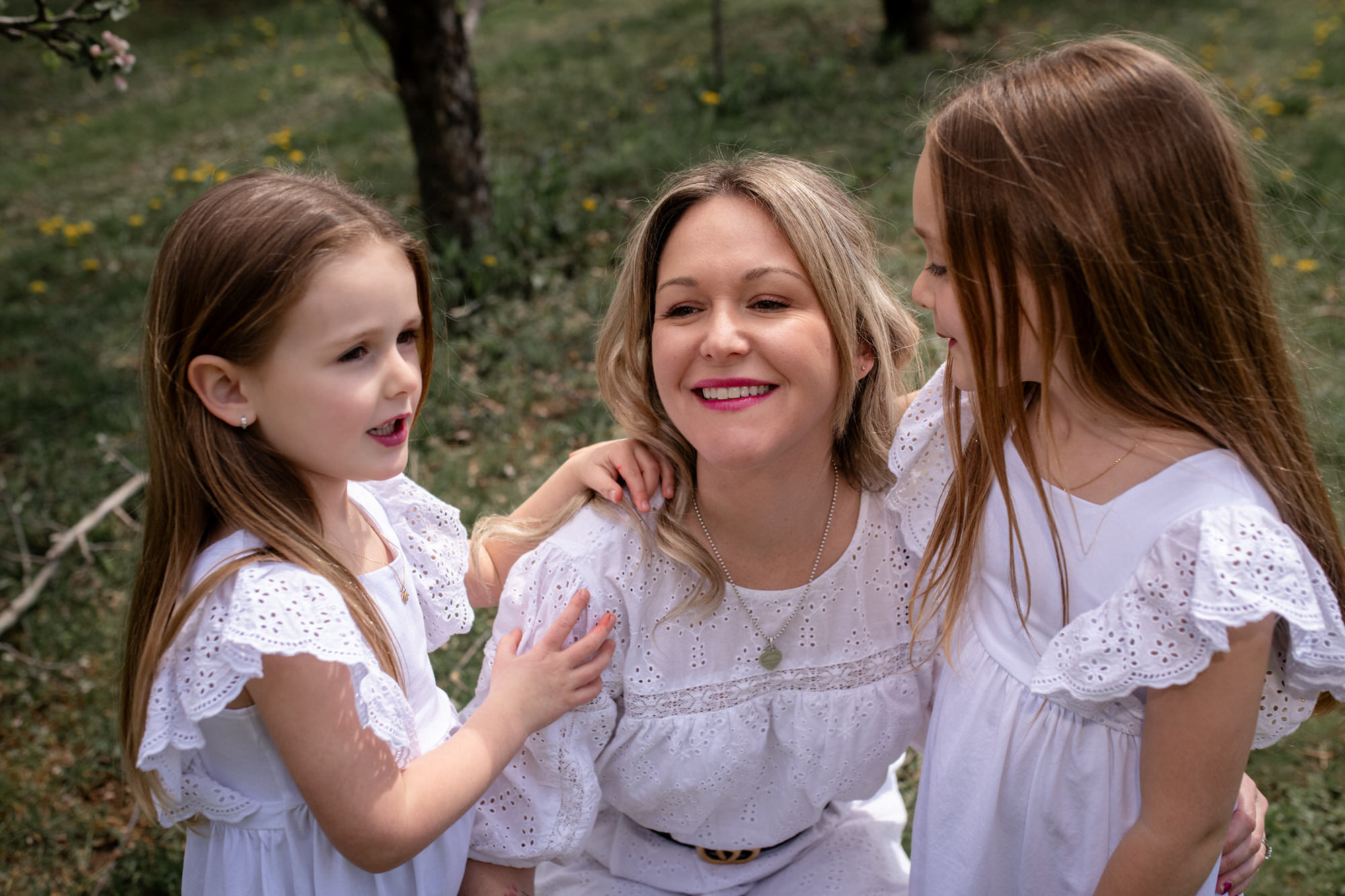 Photo paysage d'une maman et ses deux jeunes filles en robe blanche