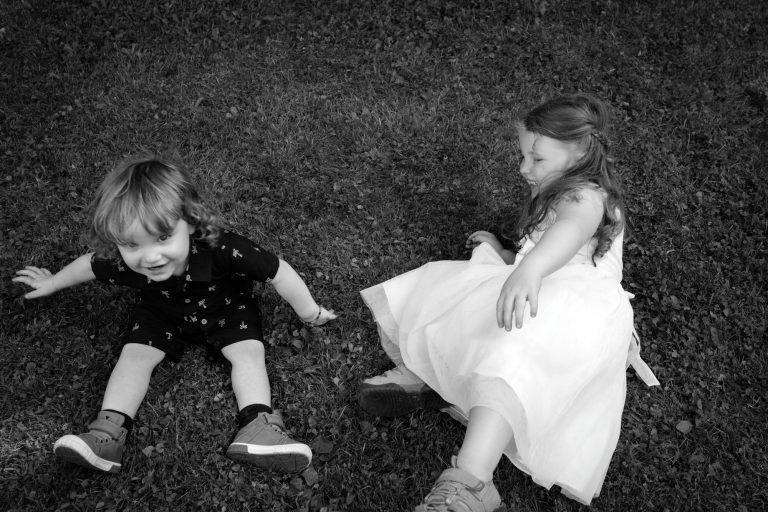 Photo en noir et blanc de deux enfants avec une jeune fille avec une robe blanche sur le gazon