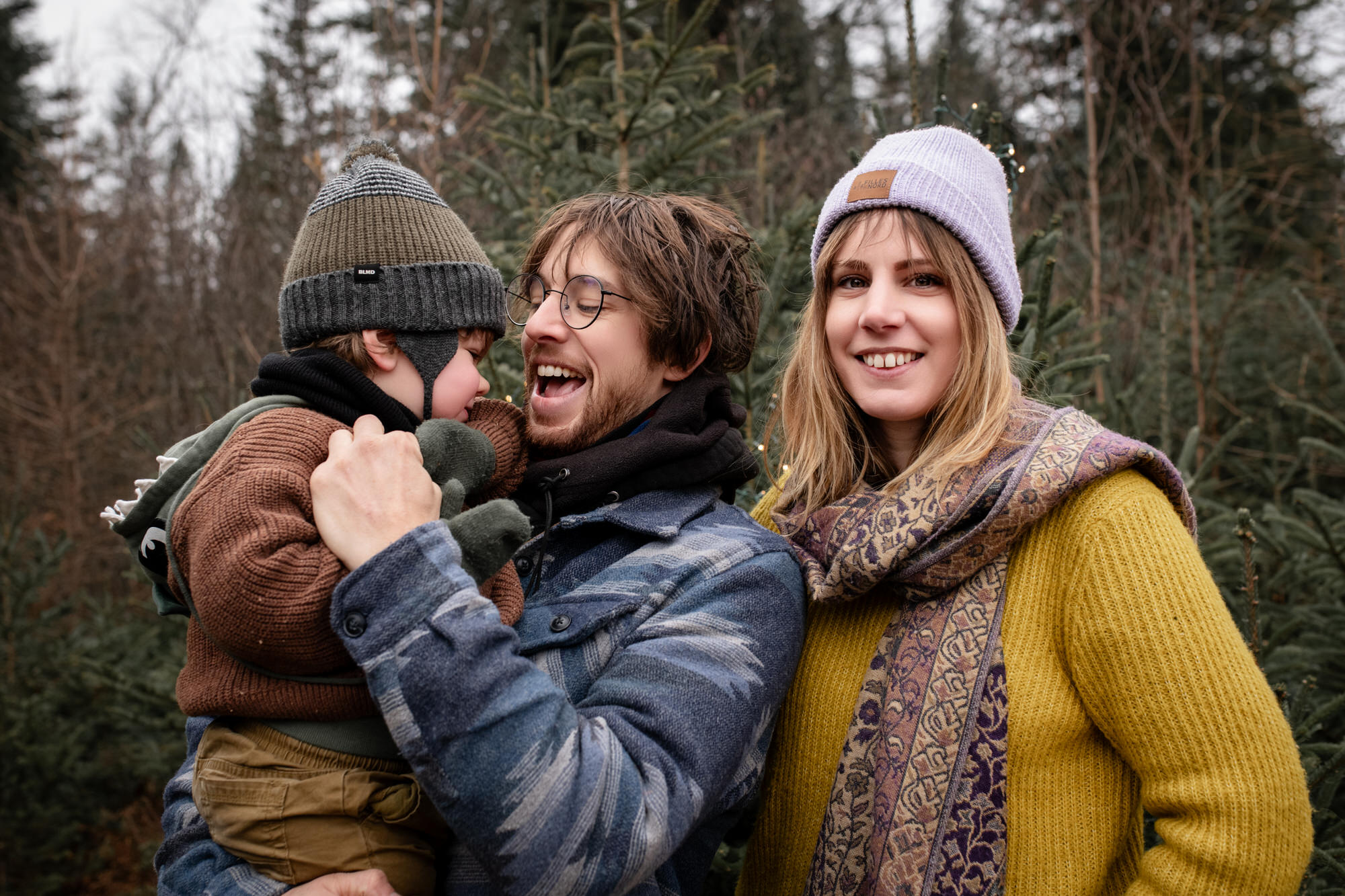 Photo d'une petite famille avec parents et un jeune garçon dans la nature avec des sapins
