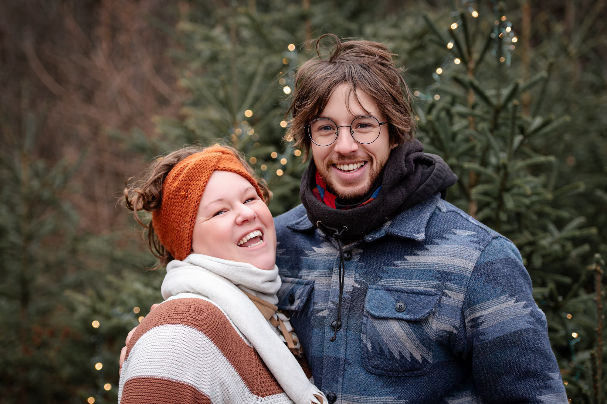 Photo d'un couple souriant à l'extérieur avec sapins