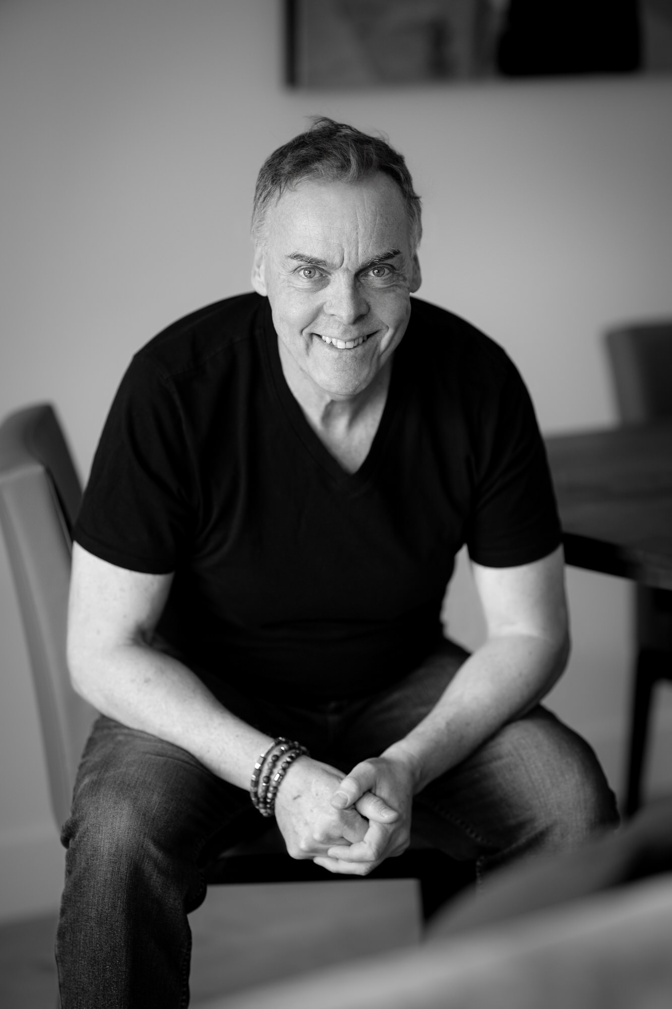 Photo d'un homme heureux souriant en noir et blanc assis à une table