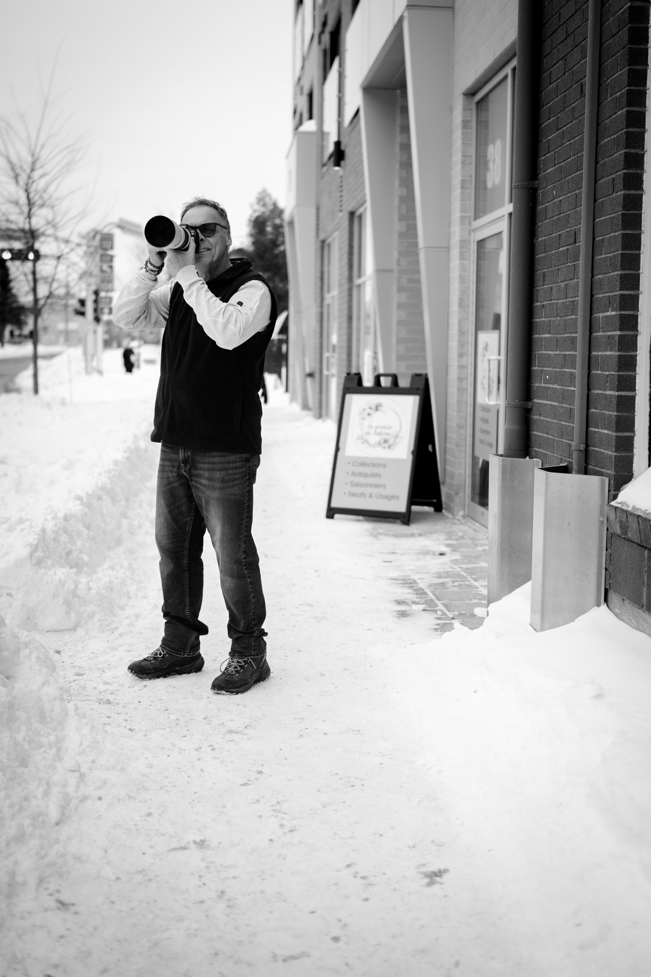 Photo d'un photographe en action pris en flagrant délit sur un trottoir enneigé