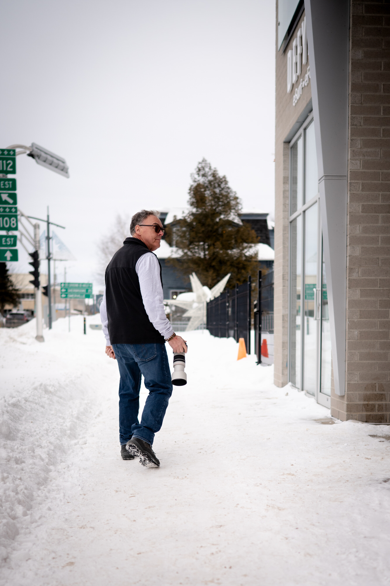 Photo d'un homme qui se promène dans la neige en ville avec son appareil-photo