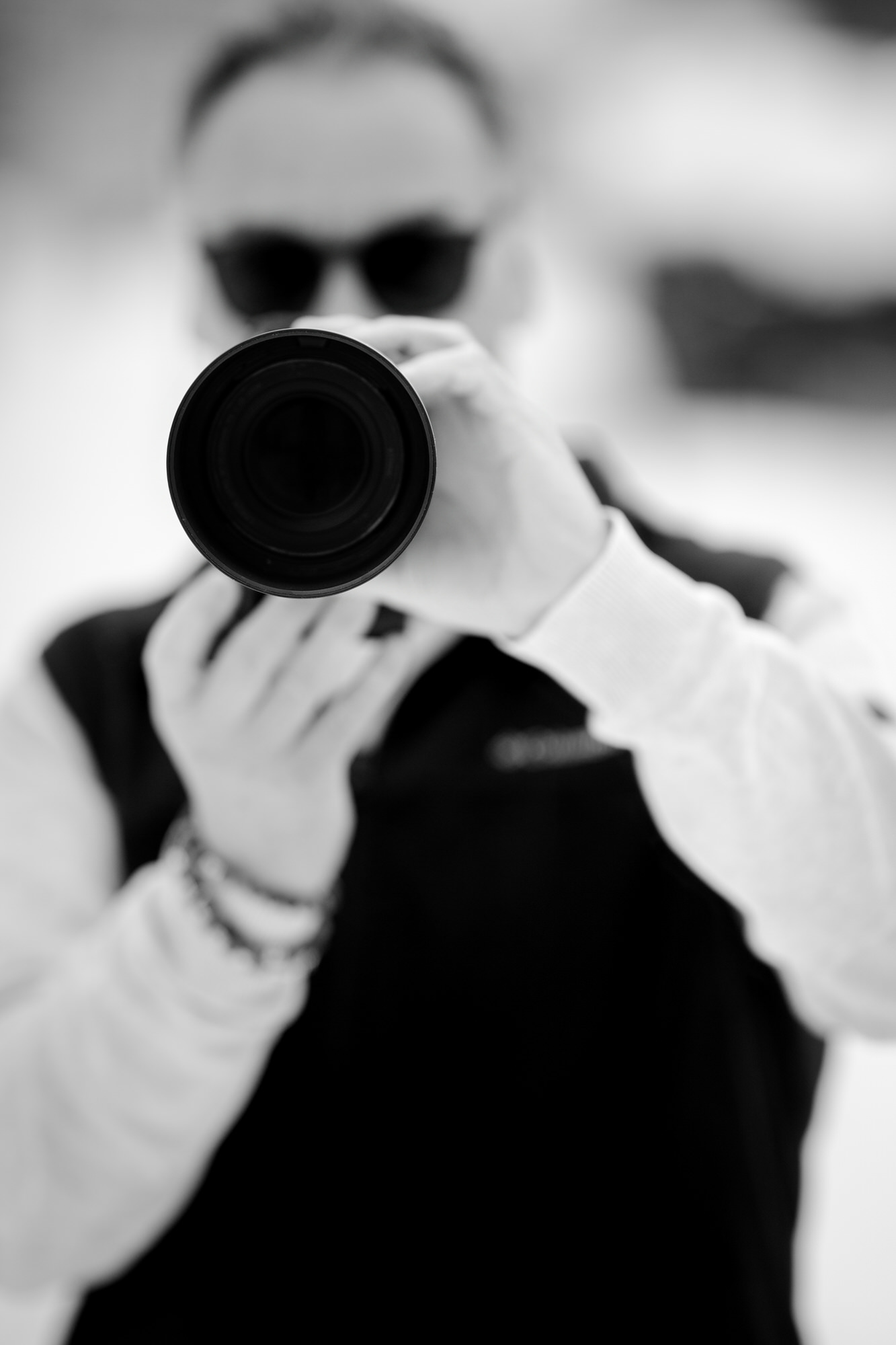 Focus sur un zoom d'appareil photo avec le photographe en arrière-plan en noir et blanc