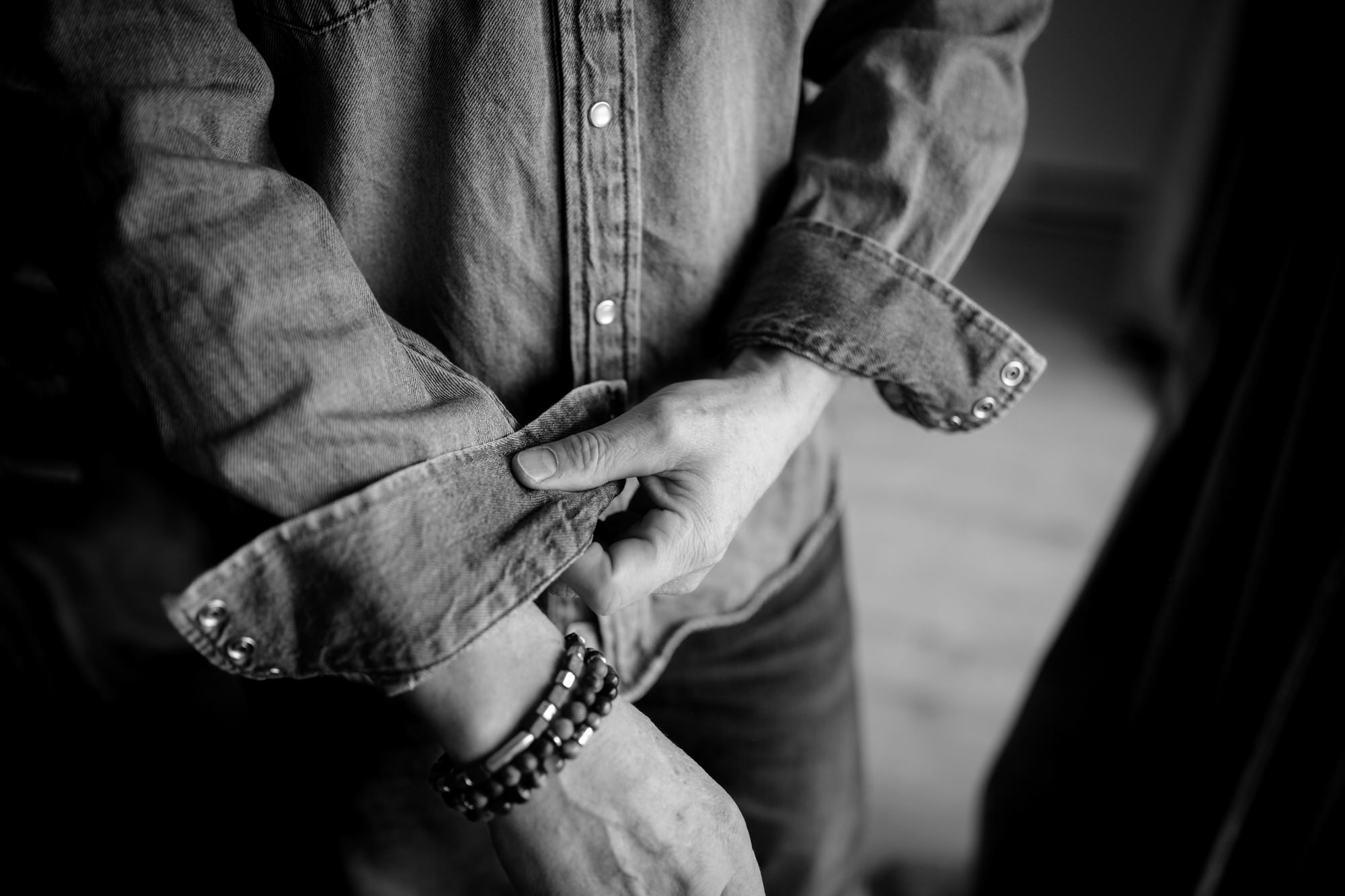 Focus sur des mains d'homme qui remonte une manche en noir et blanc